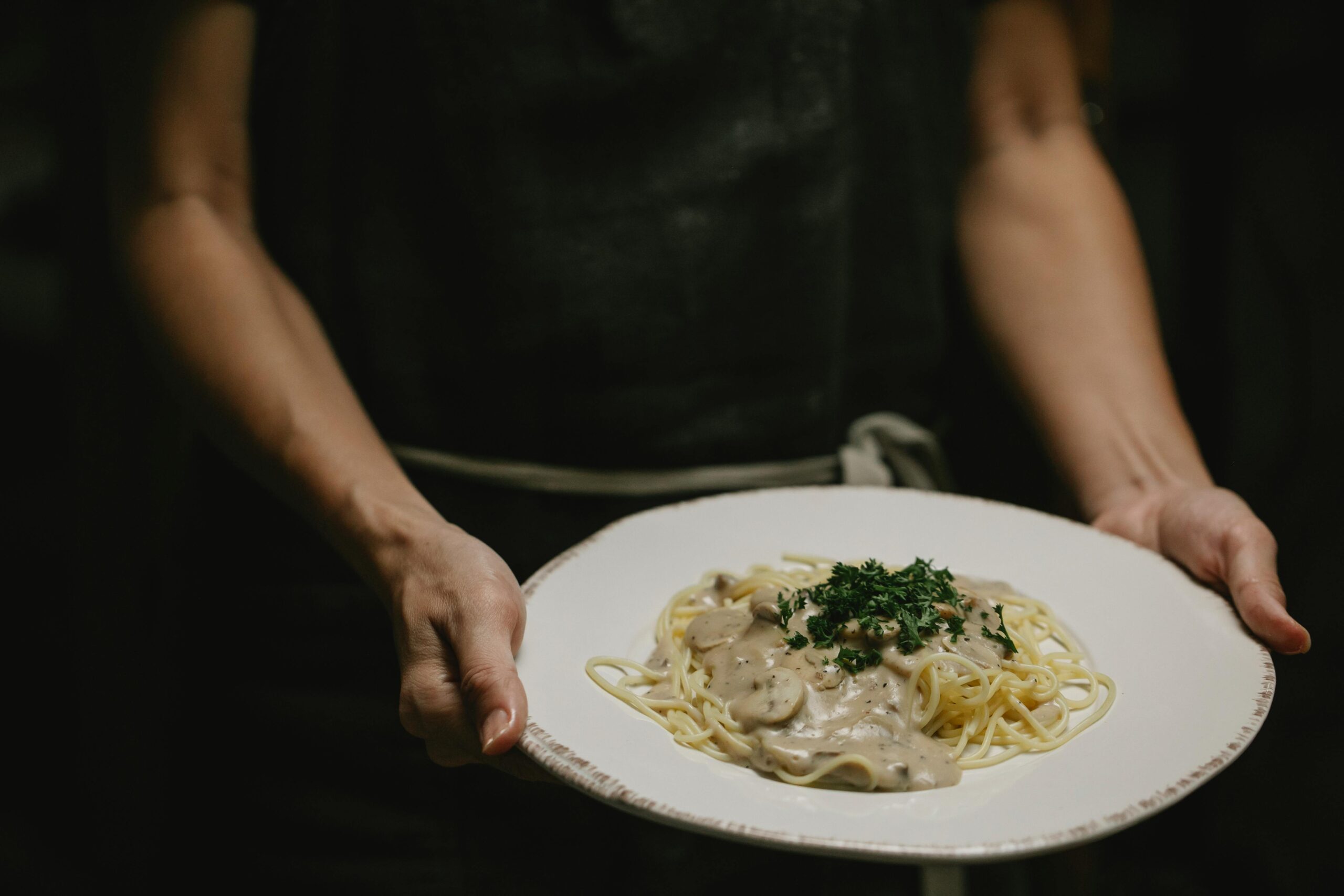 a person serving a plate of spaghetti